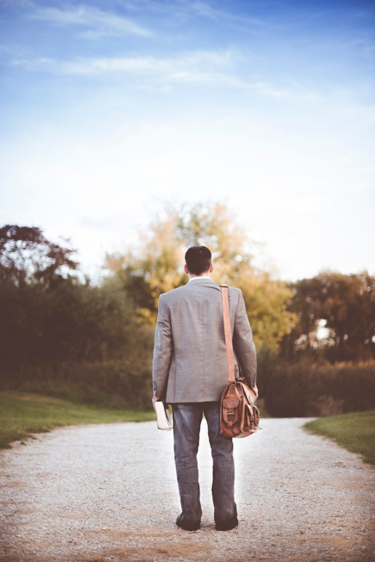 man wearing gray coat standing near road during daytime